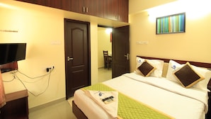 A hotel room with a bed, a TV, and a desk. - Viswa Service Apartments (Madurai)