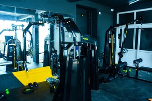 Un gimnasio con varias máquinas de ejercicio, una colchoneta amarilla y pesas.