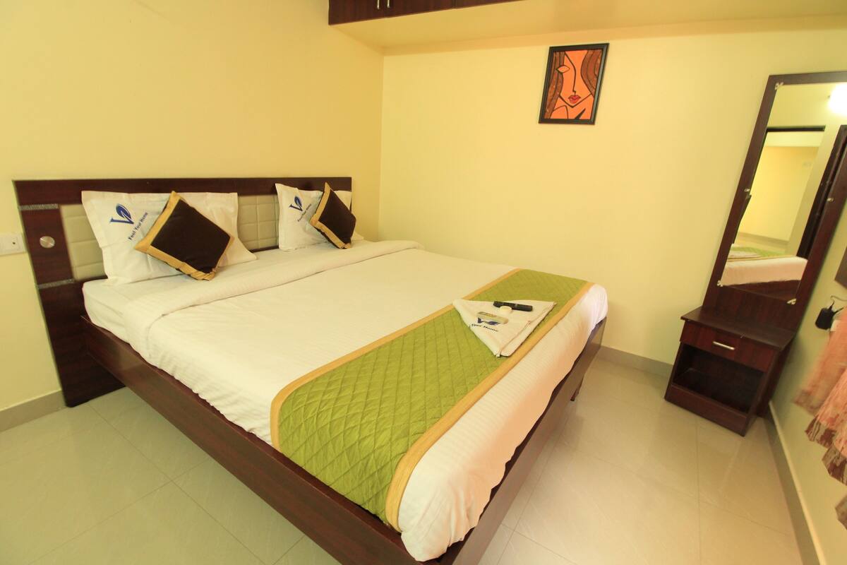 A neatly made bed with a green quilt, a wooden headboard, and a small wooden nightstand with a mirror.