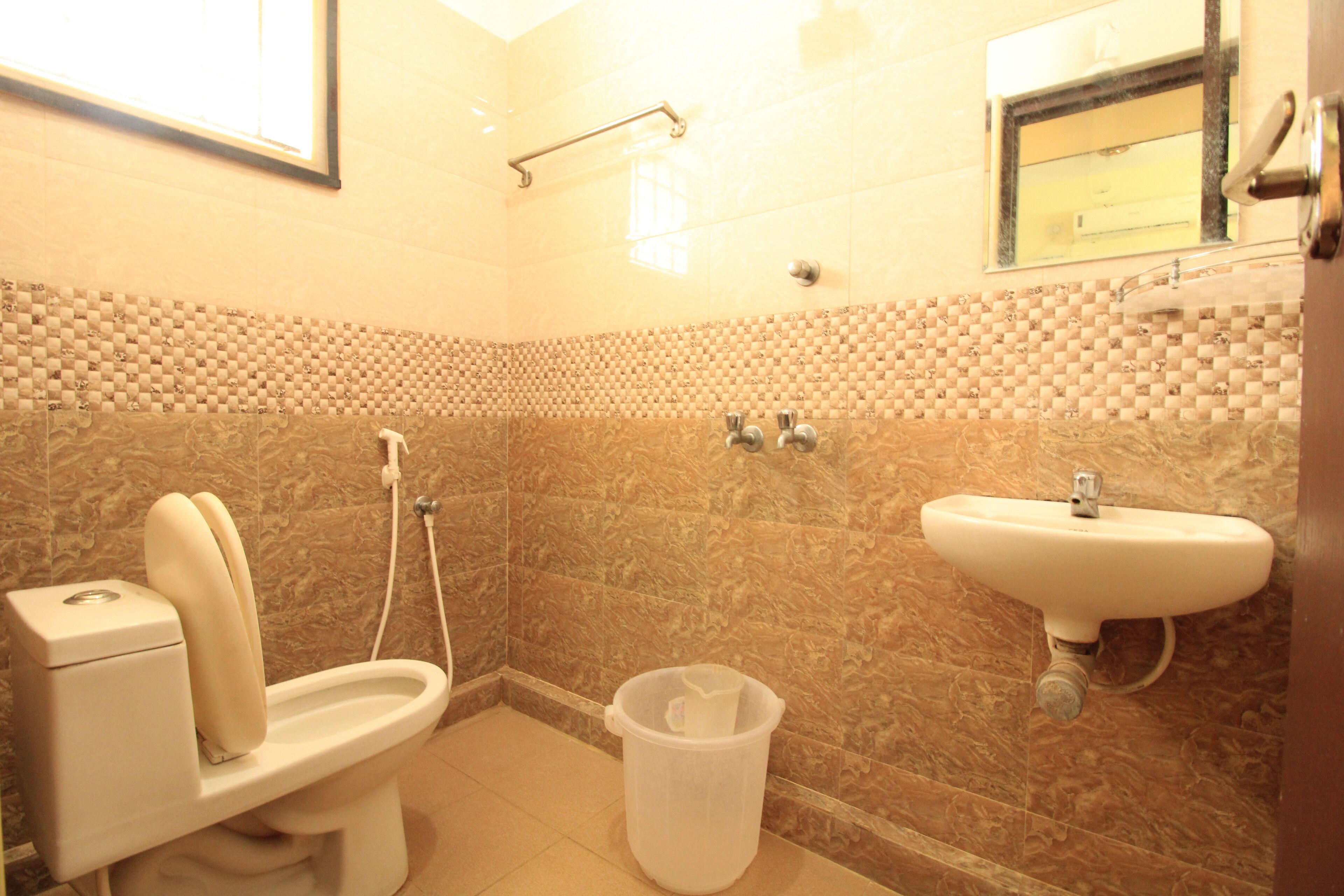A bathroom with a toilet, bidet, sink, and a trash bin.