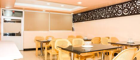 A conference room with multiple tables and chairs, a whiteboard, and a decorative wall panel.