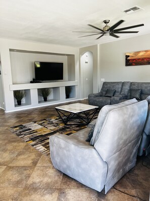Relax in this stylish living room with a large sofa, armchair, flat-screen TV, and area rug.