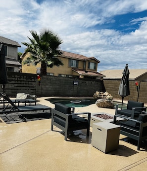 Relax by the pool surrounded by a low wall and lounge chairs, with a palm tree adding to the tropical ambiance.