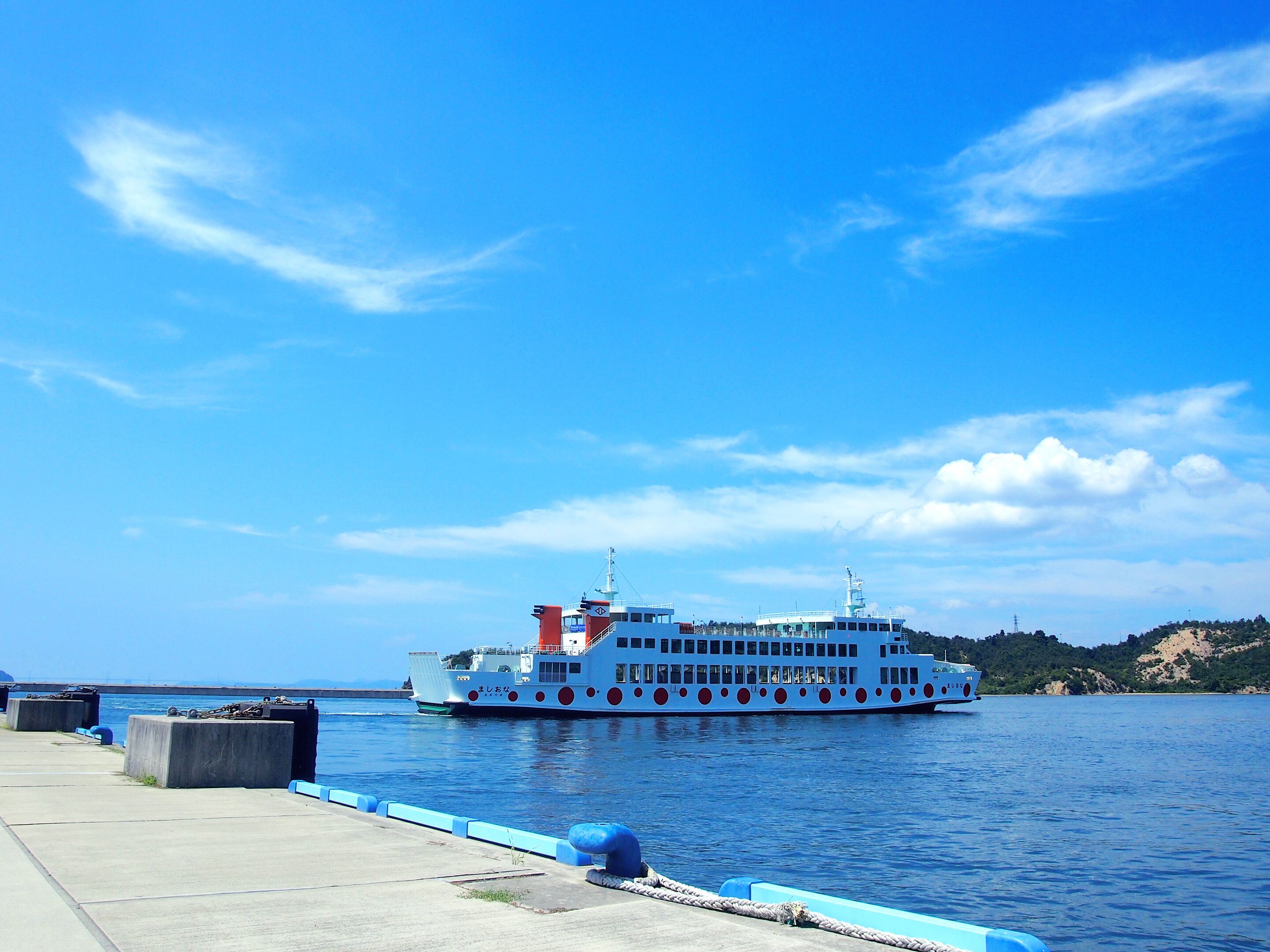 Un ferry grande y colorido atracado en un muelle, bajo un cielo azul despejado y con aguas tranquilas.