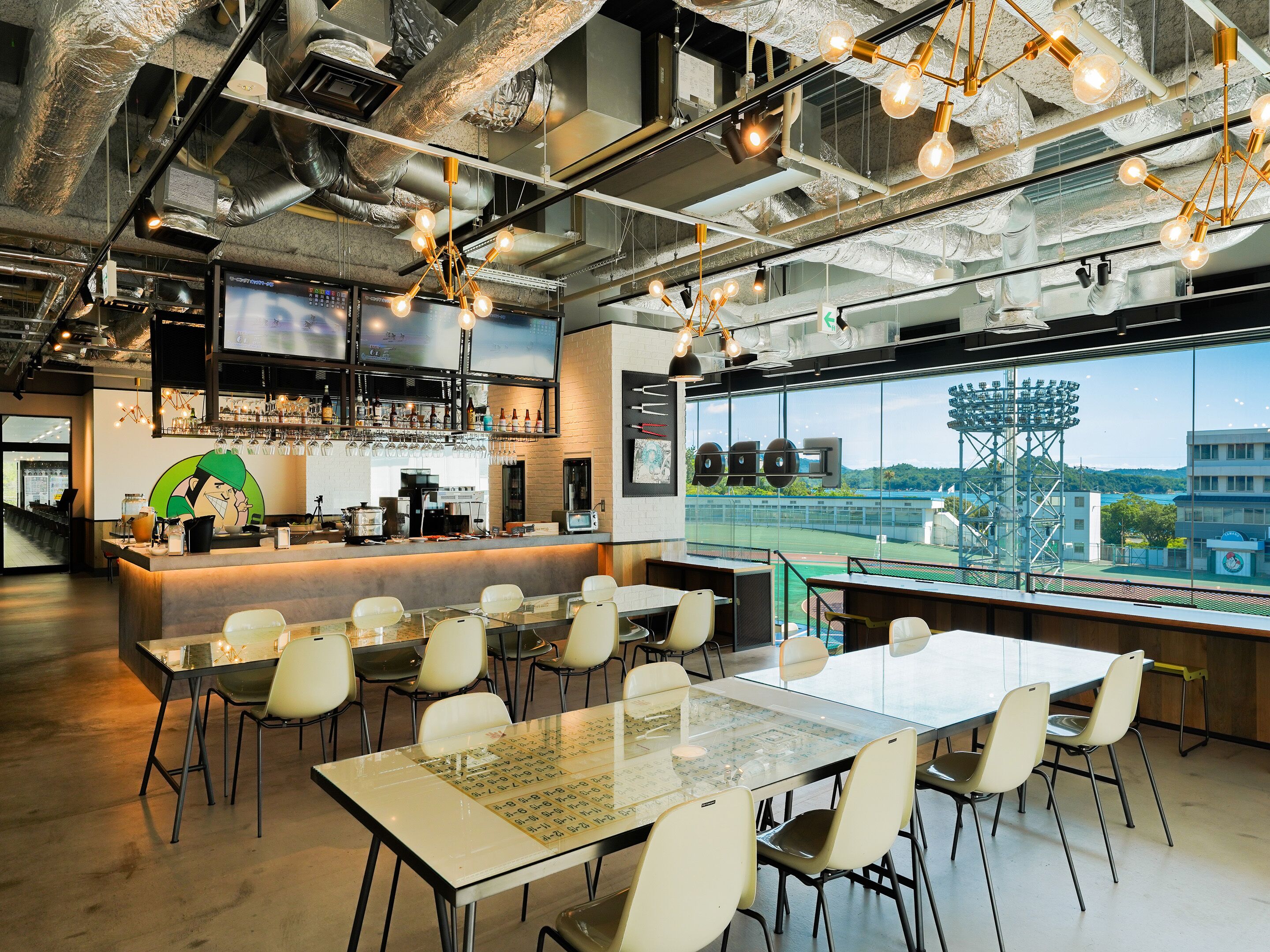 A modern restaurant with a bar area, seating, and a large window offering a view of the city.