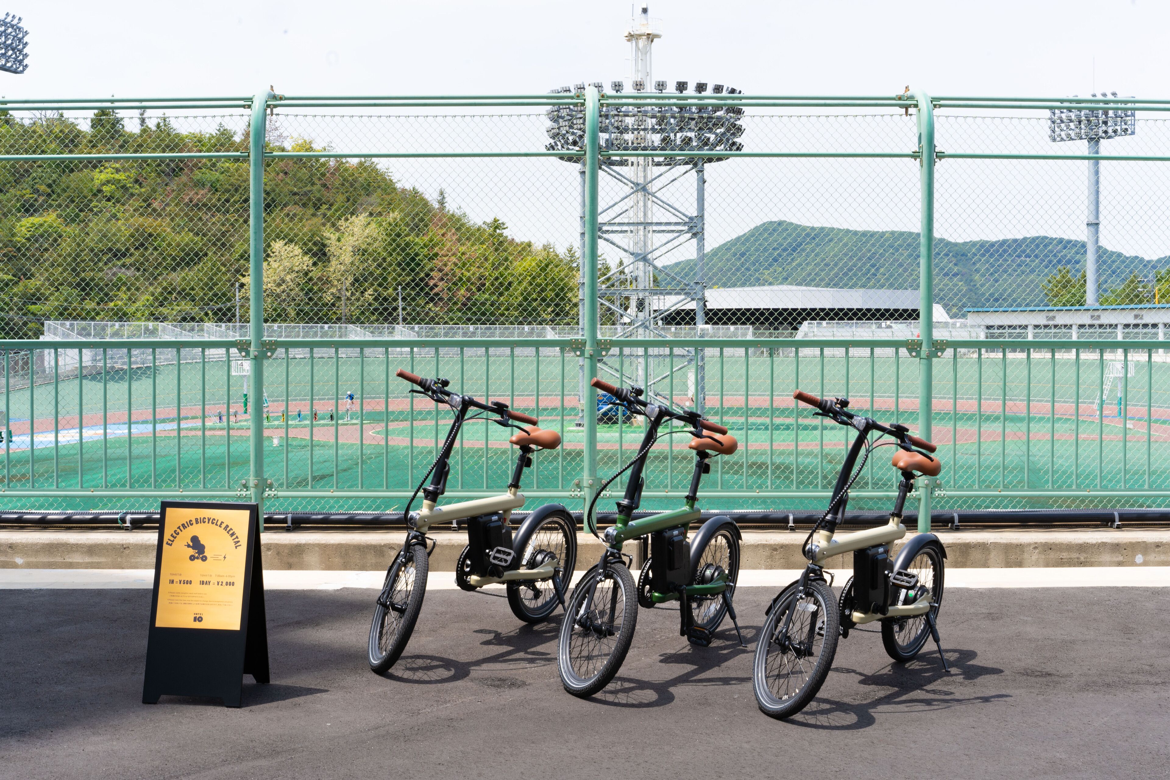 A row of electric bicycles parked in a designated area with a sign indicating the rental period.