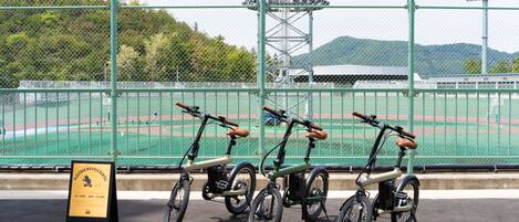Uma fileira de bicicletas elétricas estacionadas em área demarcada, com placa indicando o período de aluguel.