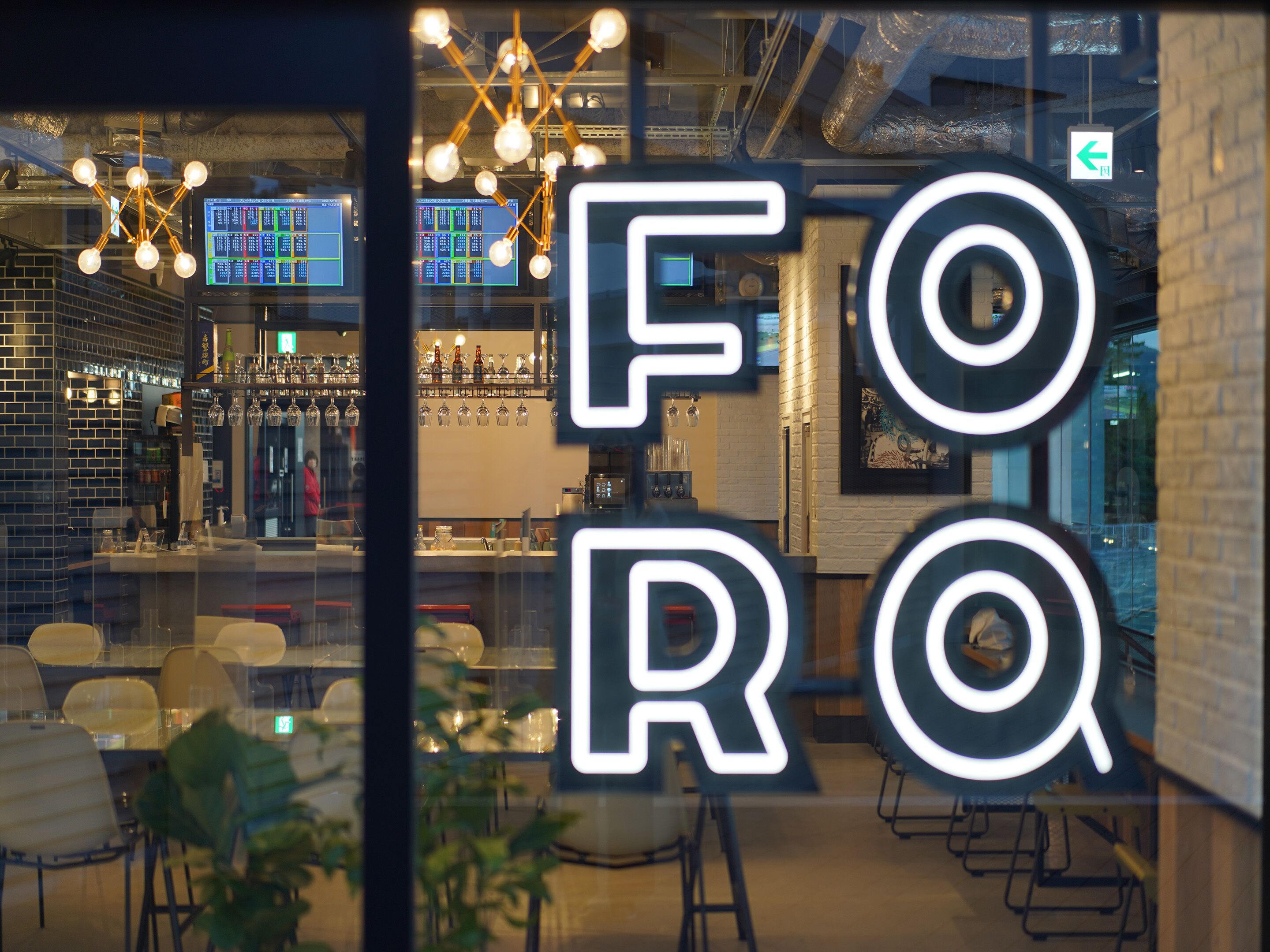 A bar area with a modern design, including a visible bar counter, seating area, and a large illuminated sign.