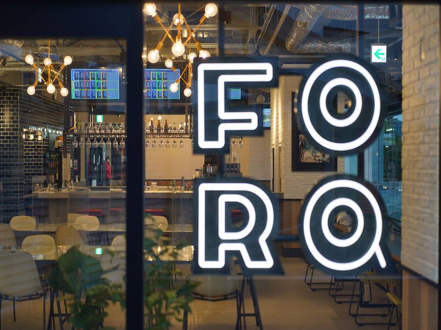 A bar area with a modern design, including a visible bar counter, seating area, and a large illuminated sign.