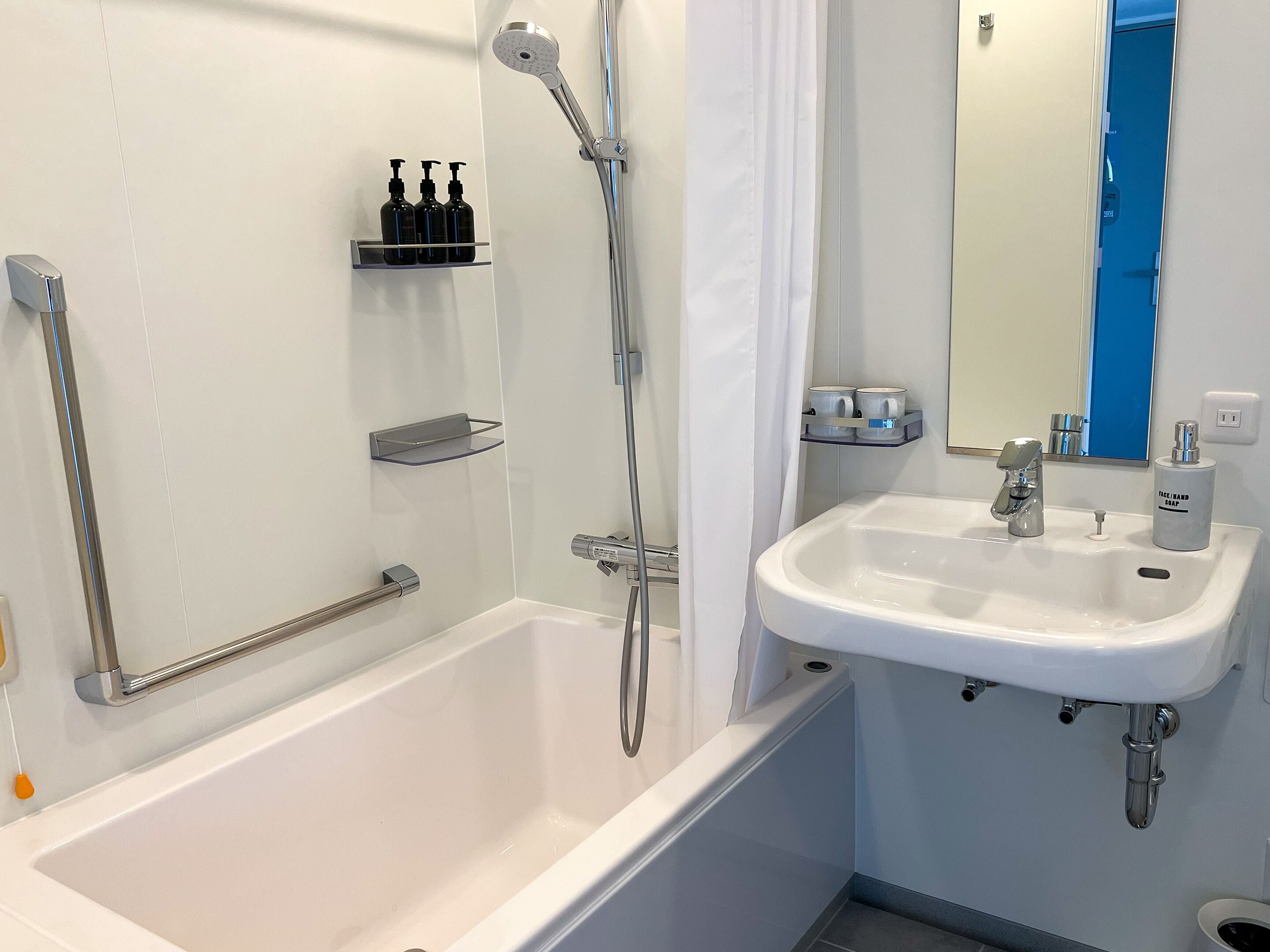A modern bathroom with a bathtub, a sink, and a shower. There are shelves with toiletries and a mirror above the sink.