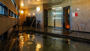 A modern indoor pool area with a glass barrier, metal railings, and a tiled floor. - SETOUCHI KEIRIN HOTEL 10 by Onko Chishin (Tamano)