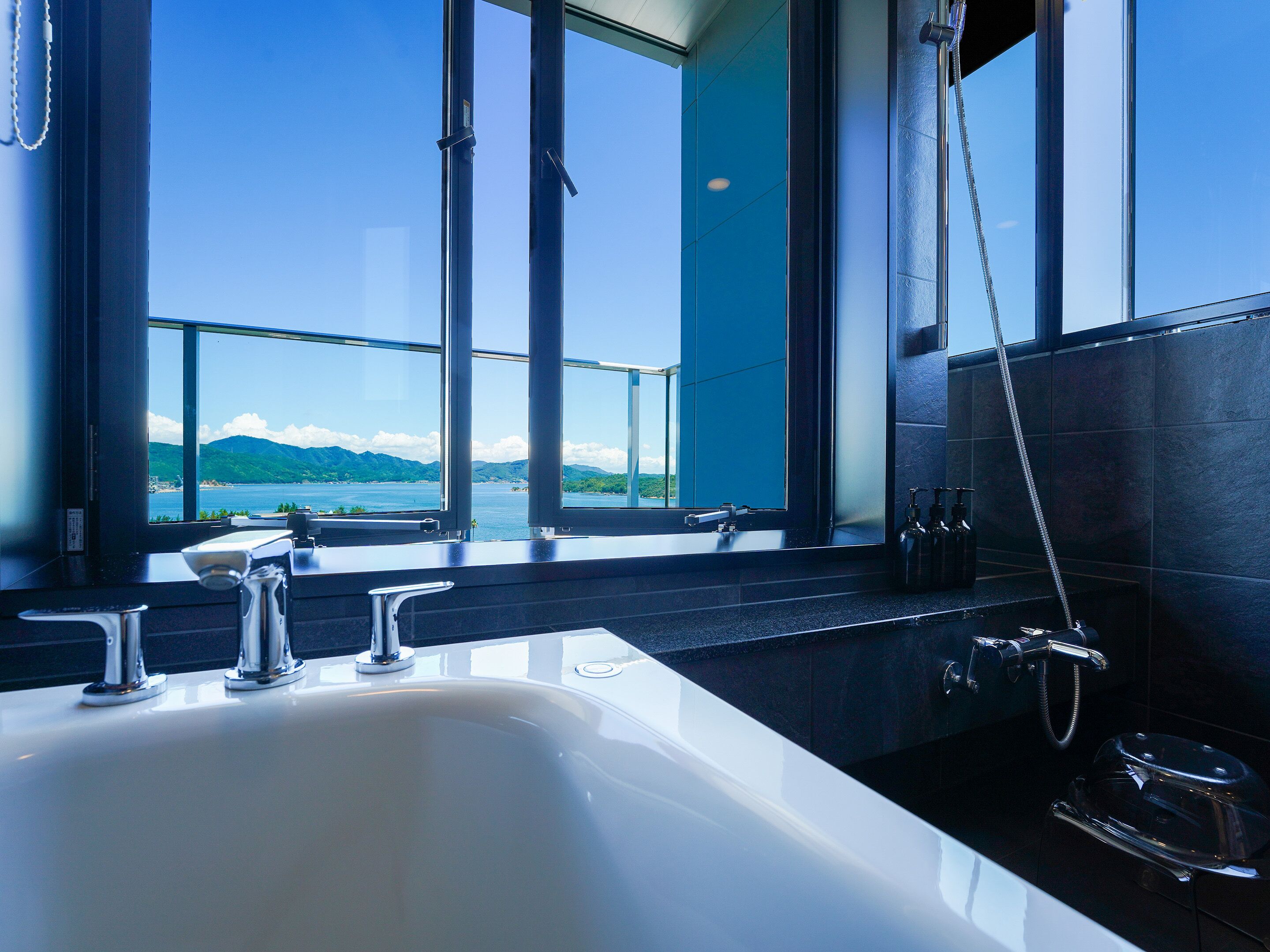 A modern bathroom with a large window offering a view of a lake and mountains.