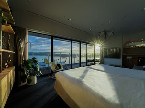 A modern hotel room with a large bed, a balcony with a view of the water, and a dining area with a table and chairs. - SETOUCHI KEIRIN HOTEL 10 by Onko Chishin (Tamano)