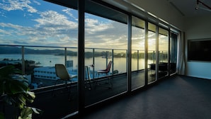A modern room with large windows offering a view of a lake and mountains. There are two chairs and a table by the windows. - SETOUCHI KEIRIN HOTEL 10 by Onko Chishin (Tamano)