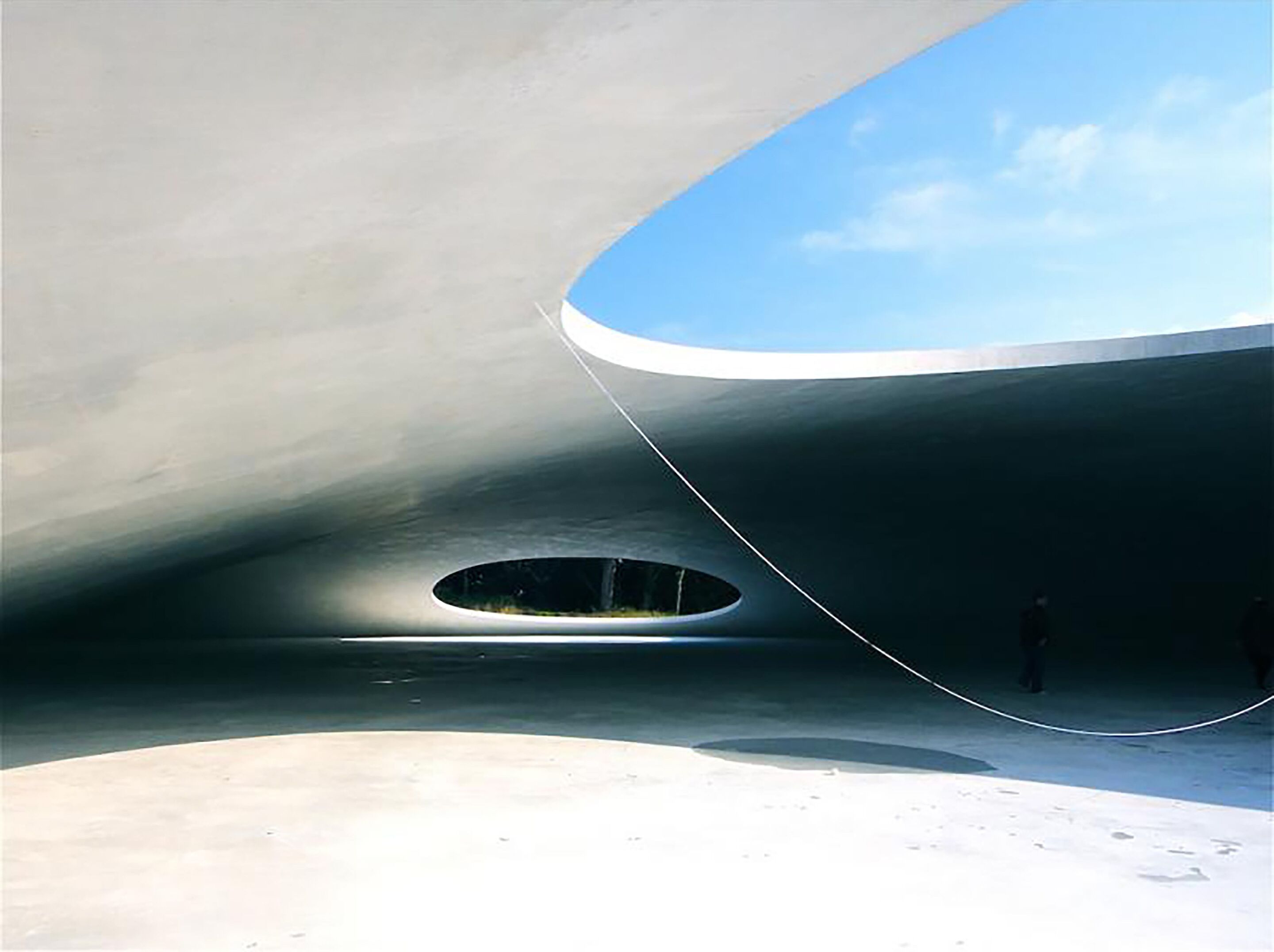 Una estructura arquitectónica moderna con un amplio orificio circular y un voladizo curvo.