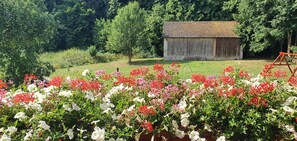 Um celeiro rústico num jardim exuberante com flores vibrantes.