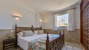 A bedroom with a wooden bed, two bedside tables, a window with curtains, and a wall-mounted light fixture. - JUNAI, villa for 4 pax in Benissa with private swimming pool and free wifi (Benissa)