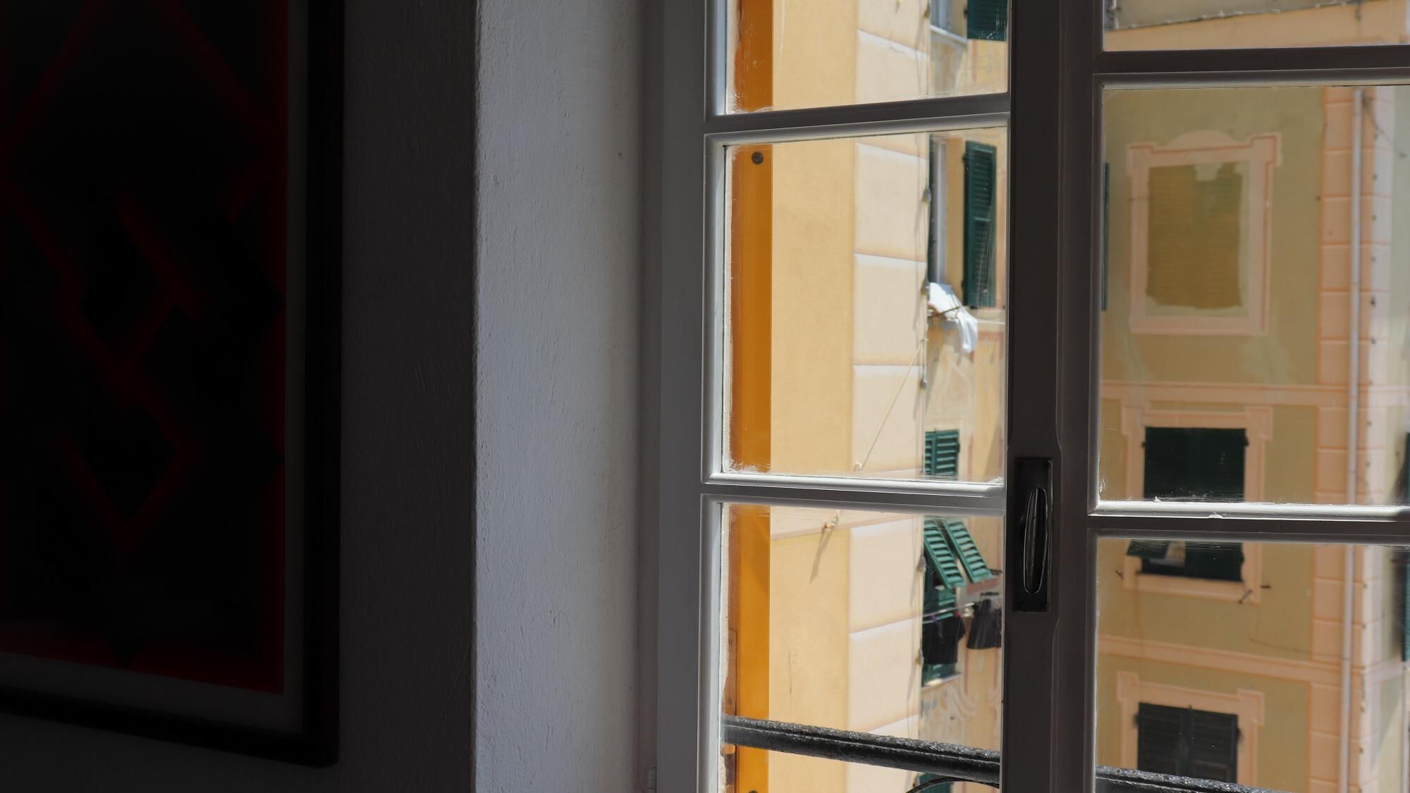 Une fenêtre donnant sur un immeuble doté de nombreuses fenêtres et de balcons.