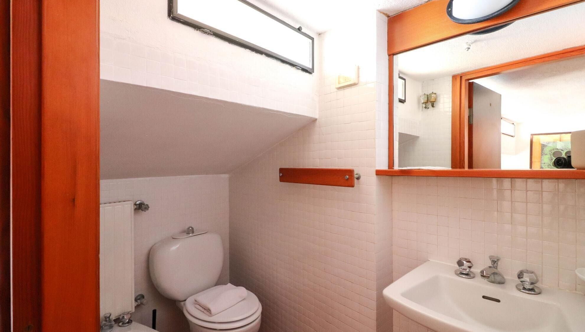 A compact bathroom with a toilet, sink, and mirror.