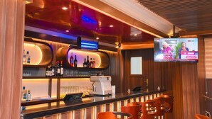 A bar area with a modern design, including a flat-screen TV, bar stools, and a coffee machine. - Golden Tulip Garden City Hotel - Rivotel (Port Harcourt)