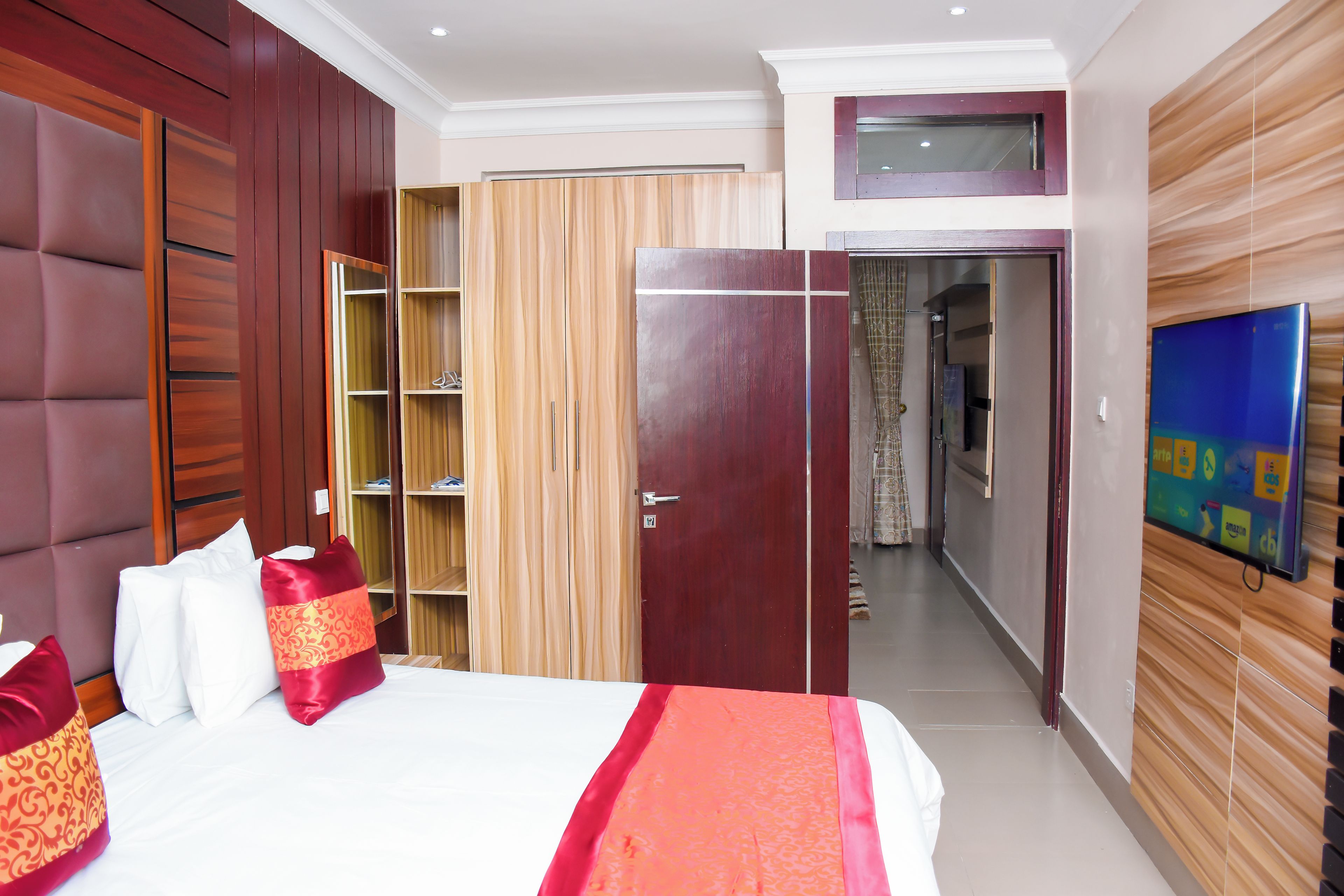 Una habitación de hotel con cama, armario y televisión en la pared.