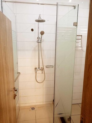 A glass-enclosed shower stall with a handheld showerhead and a wall-mounted showerhead. - Golden Tulip Garden City Hotel - Rivotel (Port Harcourt)