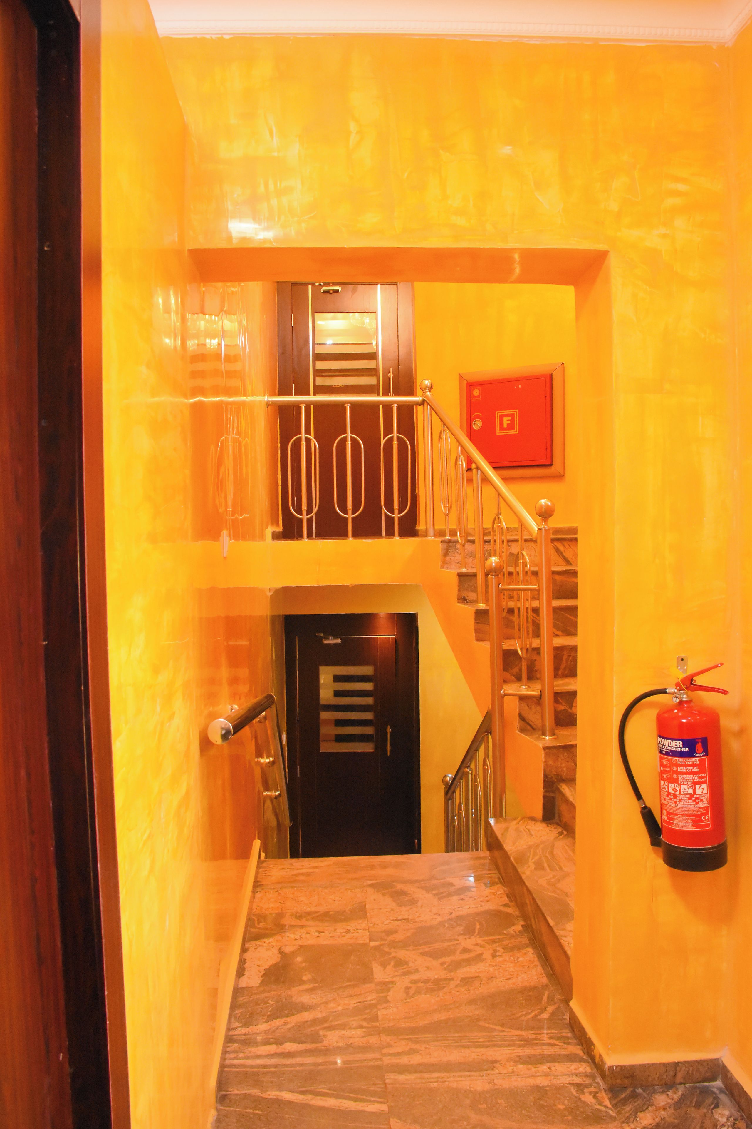 A staircase with a fire extinguisher mounted on the wall and a door at the bottom.