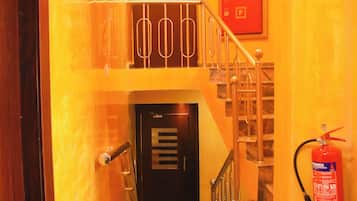 A staircase with a fire extinguisher mounted on the wall and a door at the bottom.