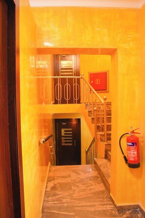 A staircase with a fire extinguisher mounted on the wall and a door at the bottom. - Golden Tulip Garden City Hotel - Rivotel (Port Harcourt)