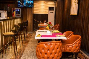 Un restaurante con sillas de cuero, una zona de bar y una pantalla de televisión.
