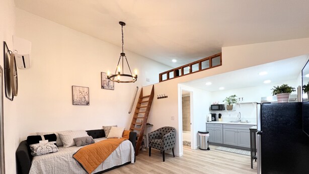 A modern apartment with a living room, kitchen, and a staircase.