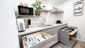 A modern kitchen with a microwave, sink, and a built-in drawer organizer.