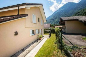 Un immeuble résidentiel doté d’un toit en pente, d’un petit jardin à l’avant et d’un chemin menant à l’entrée.