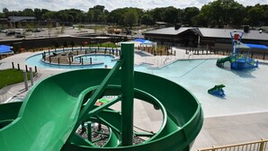En vattenpark med en stor, grön vattenrutschkana, ett poolområde och en lekplats.
