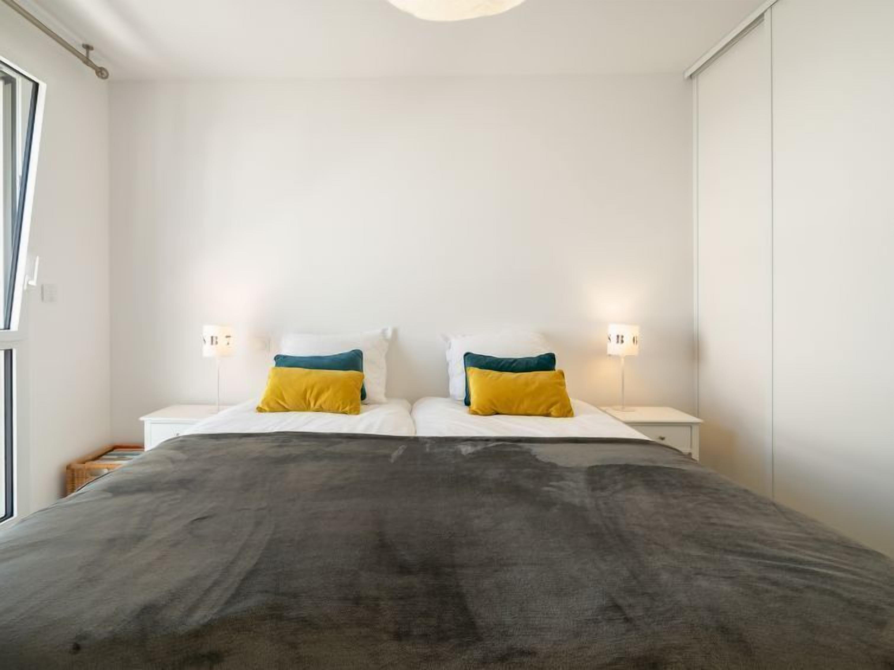 Un dormitorio con una cama grande, dos mesitas de noche y dos lámparas de pared.