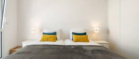 Un dormitorio con una cama grande, dos mesitas de noche y dos lámparas de pared.