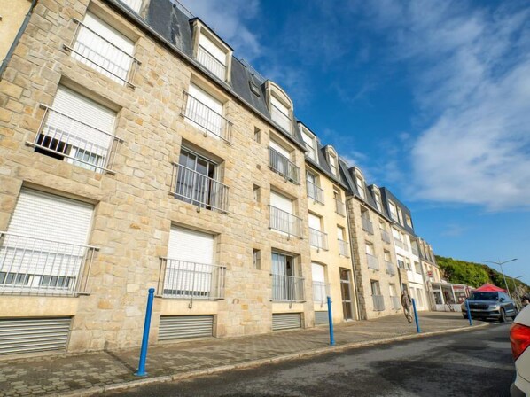 Un immeuble à plusieurs étages, doté d’une façade en pierre, de balcons et de portes de garage.