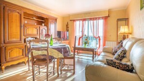 Ein Essbereich mit Holzzimmermöbeln, einem Tisch mit Tischdecke, Stühlen und einem Fenster mit Vorhängen.