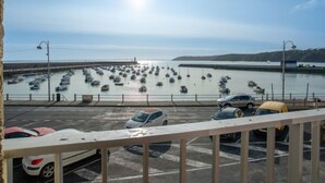 Ein Parkplatz mit Autos und Blick auf Boote im Wasser.