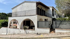 Ein zweistöckiges Gebäude mit weißer Fassade, einem Balkon und gewölbten Eingängen.
