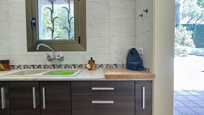 Eine moderne Küche mit Spüle, Wasserhahn und Fenster mit Blick auf Grünflächen.