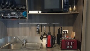 A compact kitchen with a sink, microwave, kettle, toaster, and utensils. - The Red Shed
Large modern studio on two peaceful acres, two minutes from CBD (Matamata)