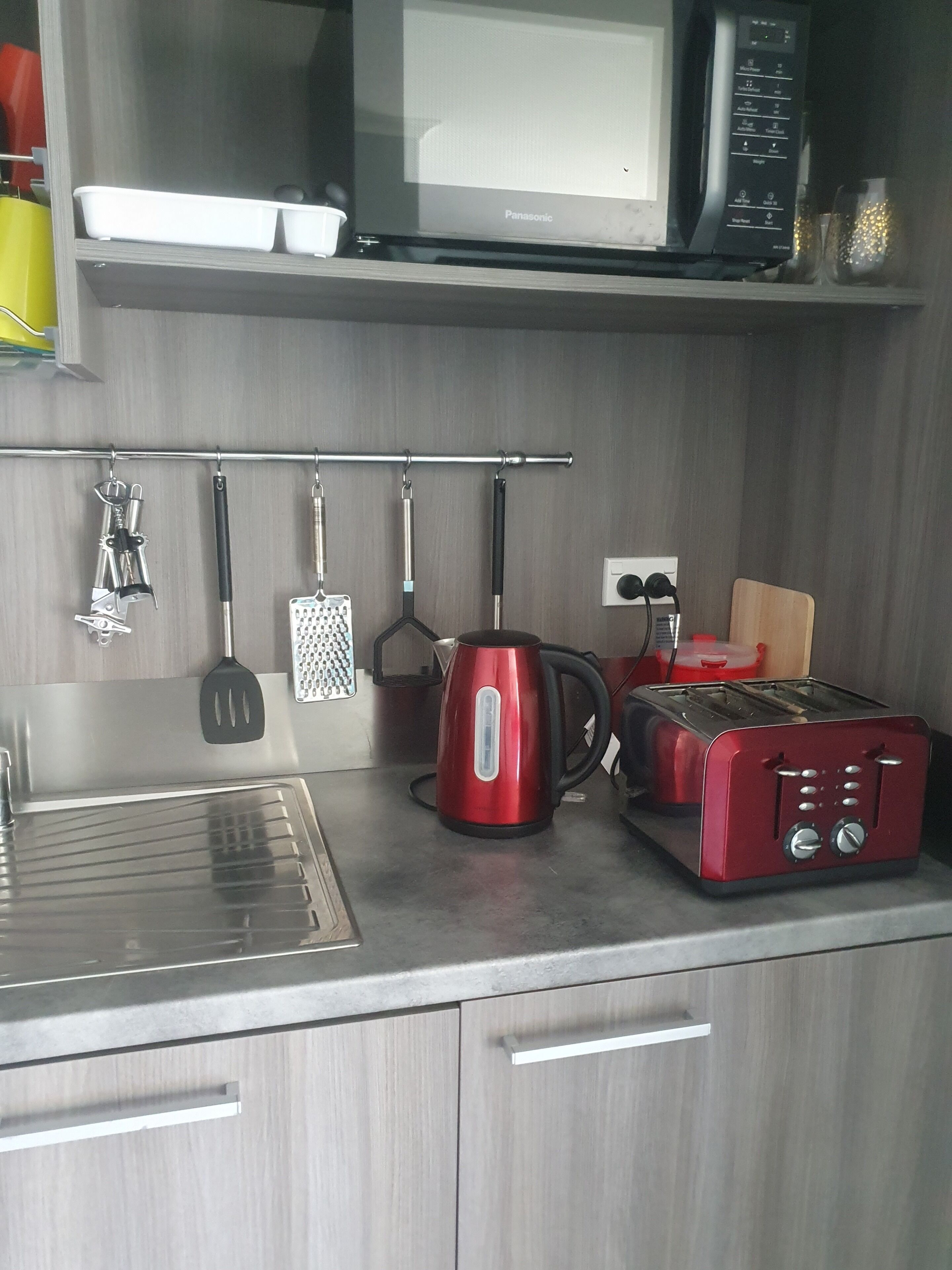Eine Küche mit Mikrowelle, Toaster, Wasserkocher und verschiedenen Küchenutensilien auf der Arbeitsfläche.