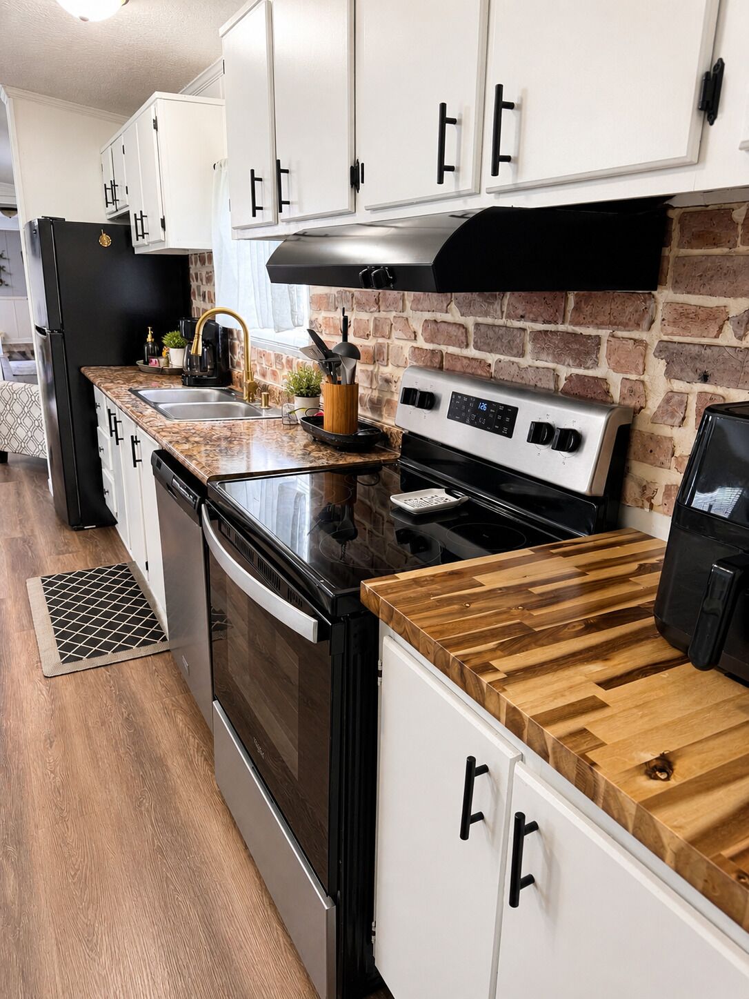 Une cuisine moderne avec des armoires blanches, une cuisinière noire et un plan de travail en bois.