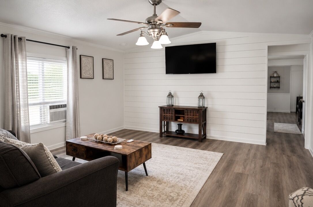 Un salon doté d’un ventilateur de plafond, d’un téléviseur à écran plat, d’une table basse en bois et d’un canapé.