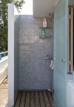 Shower area features a wall-mounted showerhead and handheld attachment.