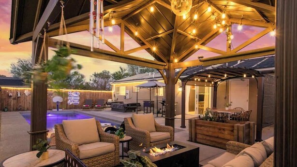 Eine Terrasse im Freien mit Korbmöbeln, einer Feuerstelle und einem Pool.