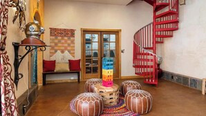 A spacious lobby with a wooden bench, a colorful stack of blocks, and a red spiral staircase.