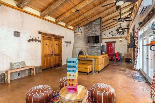 A spacious living area with a wooden ceiling, a stone fireplace, and a colorful stack of blocks.