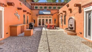A courtyard with a barbecue area, outdoor seating, and a water feature.